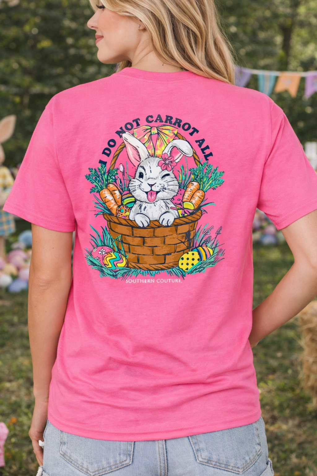 Woman wearing a pink t-shirt with an Easter bunny graphic, standing outdoors with Easter decorations in the background.
