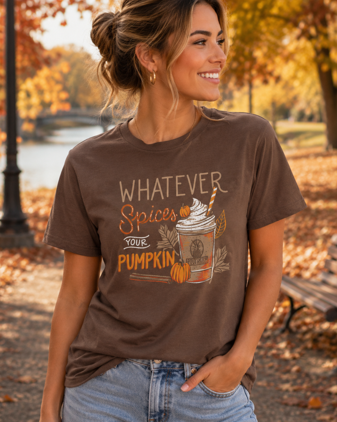 Woman wearing a brown t-shirt with a pumpkin spice latte graphic in an autumn setting.