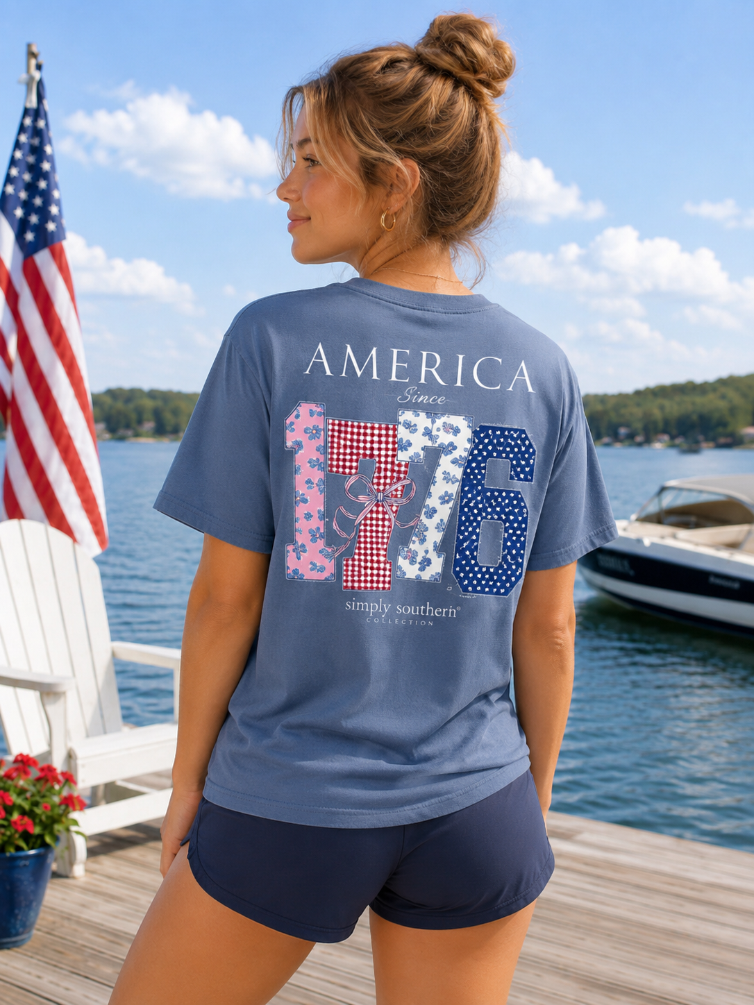 Woman wearing a blue t-shirt with 'America Since 1776' design by the water with an American flag.